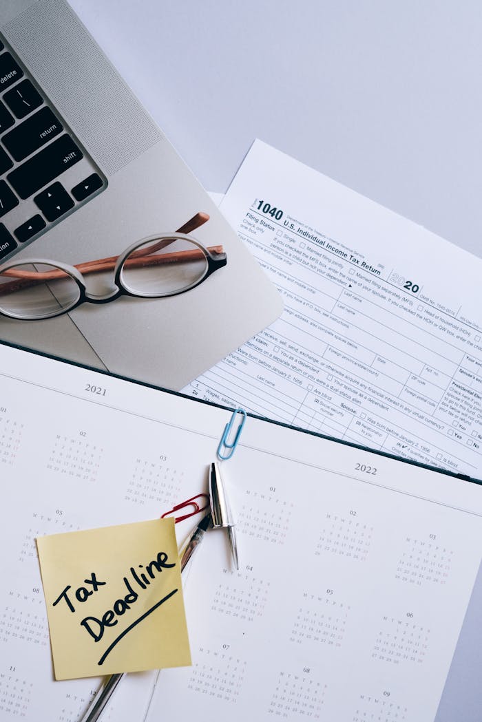 Top view of tax forms, calendar, and sticky note reminder for tax deadline.